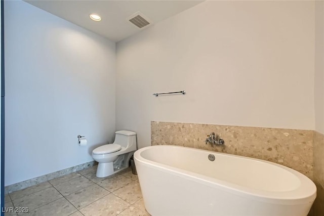 bathroom with baseboards, visible vents, a freestanding tub, tile patterned floors, and toilet