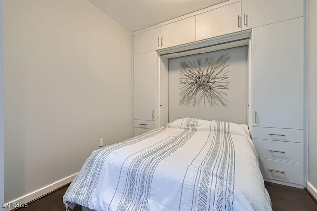 bedroom featuring dark wood-type flooring, baseboards, and a closet