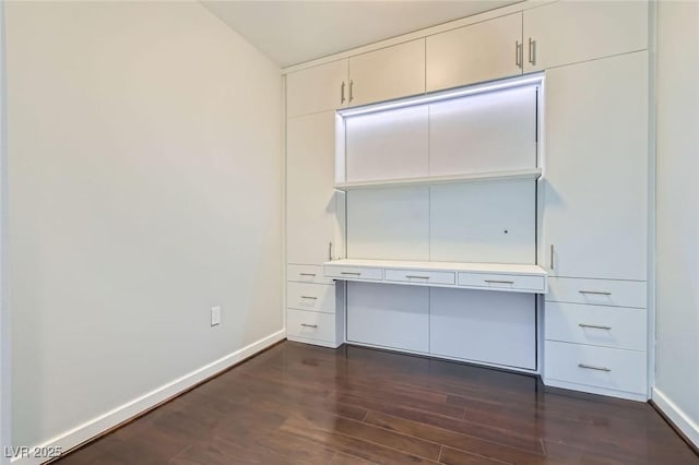 unfurnished office featuring dark wood-type flooring and baseboards