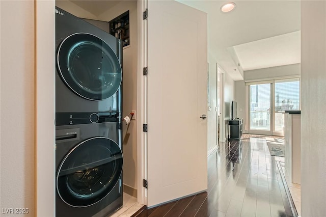 washroom featuring stacked washer and clothes dryer, wood finished floors, and laundry area