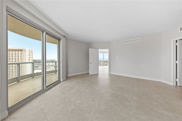 empty room featuring light tile patterned floors, visible vents, and baseboards