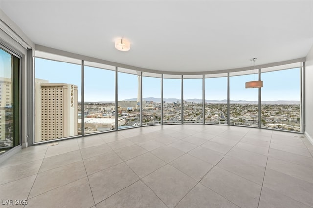 spare room with a wealth of natural light, a mountain view, floor to ceiling windows, and tile patterned floors