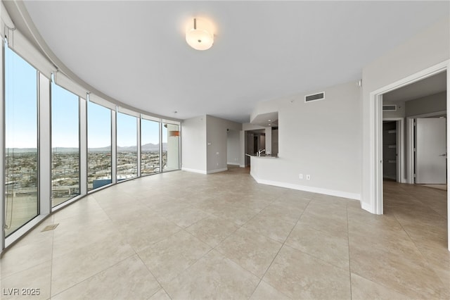 unfurnished living room with visible vents, baseboards, and floor to ceiling windows