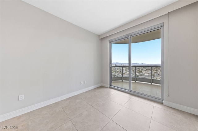 unfurnished room featuring a mountain view, light tile patterned floors, and baseboards