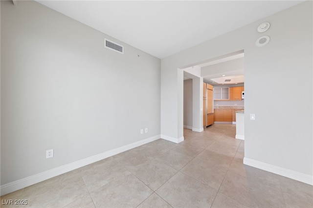 empty room featuring light tile patterned floors, baseboards, and visible vents