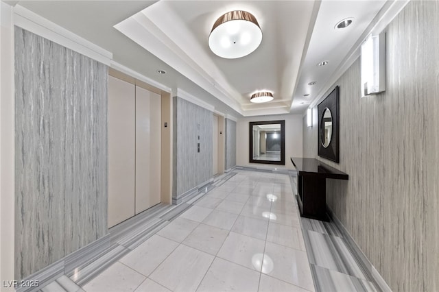 corridor with light tile patterned floors, a tray ceiling, and elevator