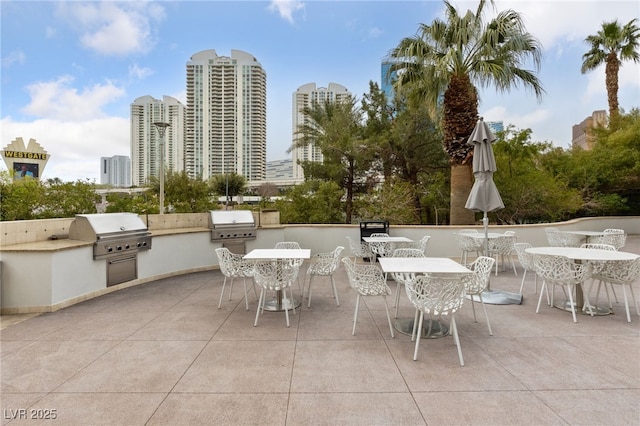 view of patio featuring an outdoor kitchen, a view of city, outdoor dining area, and a grill