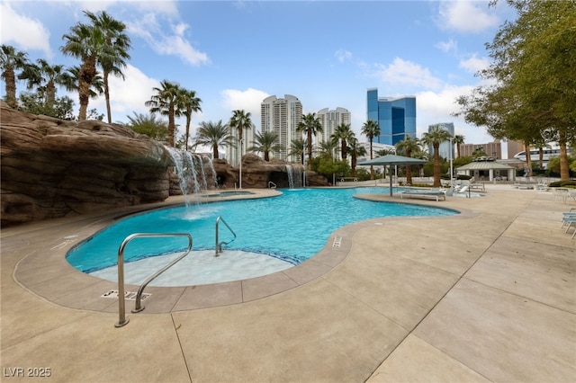 community pool with a patio area, a view of city, and a hot tub