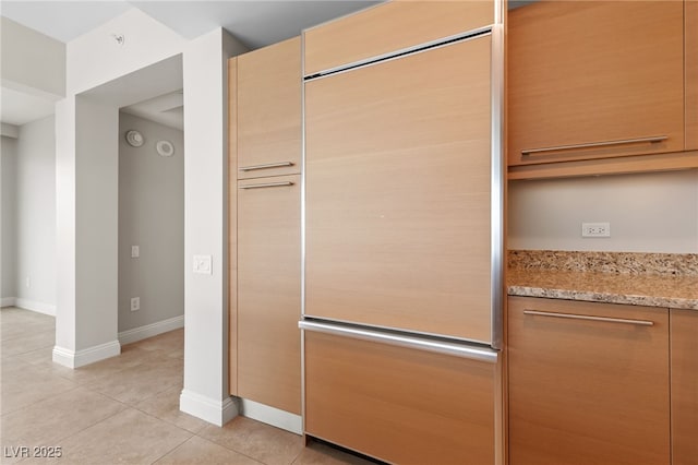 kitchen with light tile patterned flooring, baseboards, light stone counters, and modern cabinets