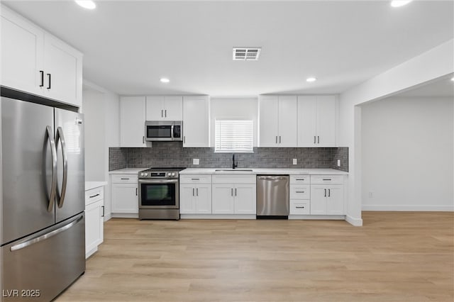 kitchen with a sink, stainless steel appliances, visible vents, and light countertops