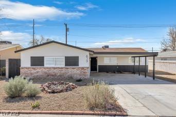 ranch-style home featuring brick siding, concrete driveway, and fence