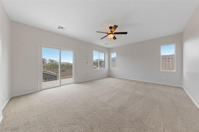 empty room featuring light carpet, visible vents, baseboards, and a ceiling fan