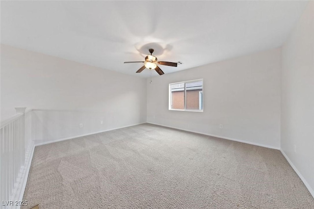 carpeted empty room featuring a ceiling fan and baseboards