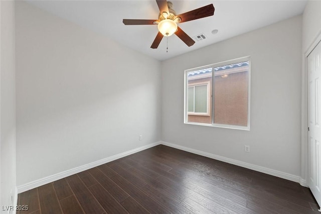 spare room featuring visible vents, baseboards, a ceiling fan, and dark wood-style flooring