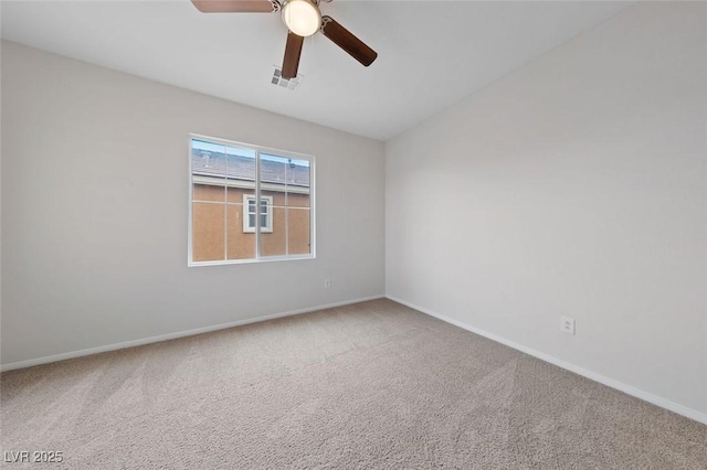 carpeted spare room with visible vents, baseboards, and a ceiling fan