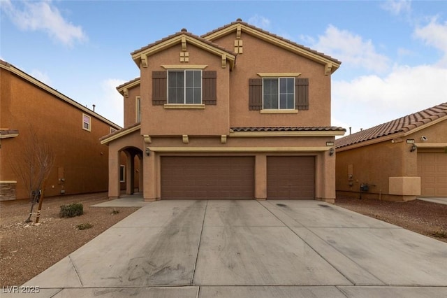 view of front of property featuring concrete driveway, a tiled roof, an attached garage, and stucco siding