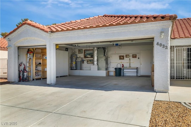 garage featuring concrete driveway, a garage door opener, and water heater