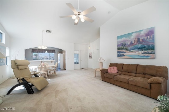 living room with visible vents, high vaulted ceiling, ceiling fan with notable chandelier, arched walkways, and carpet