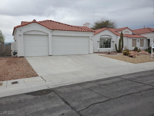 mediterranean / spanish home with stucco siding, a tile roof, concrete driveway, an attached garage, and a chimney