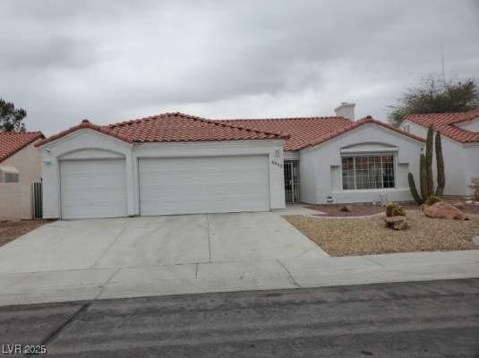 mediterranean / spanish home with a tiled roof, a garage, driveway, and a chimney