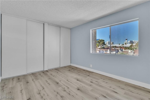 unfurnished room with wood finished floors, baseboards, and a textured ceiling