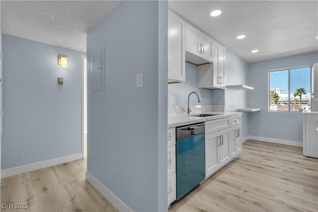 kitchen featuring white cabinetry, dishwashing machine, baseboards, and a sink