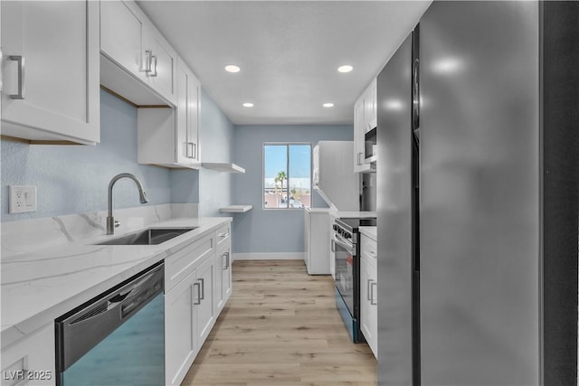 kitchen with light stone counters, a sink, stainless steel appliances, light wood-style floors, and white cabinetry