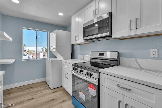 kitchen with white cabinetry, light wood-style floors, stacked washer and clothes dryer, and stainless steel appliances