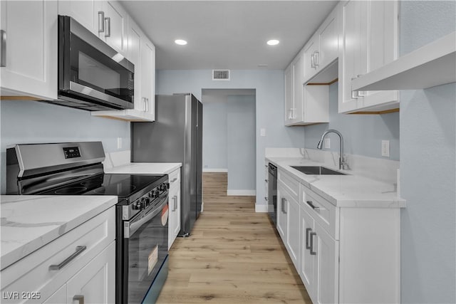 kitchen with visible vents, a sink, white cabinetry, stainless steel appliances, and light stone countertops