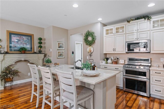 kitchen with dark wood finished floors, light countertops, glass insert cabinets, and stainless steel appliances