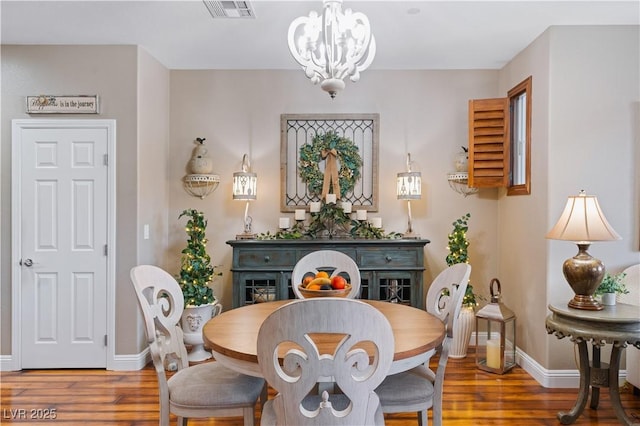 dining room featuring baseboards, wood finished floors, visible vents, and a chandelier