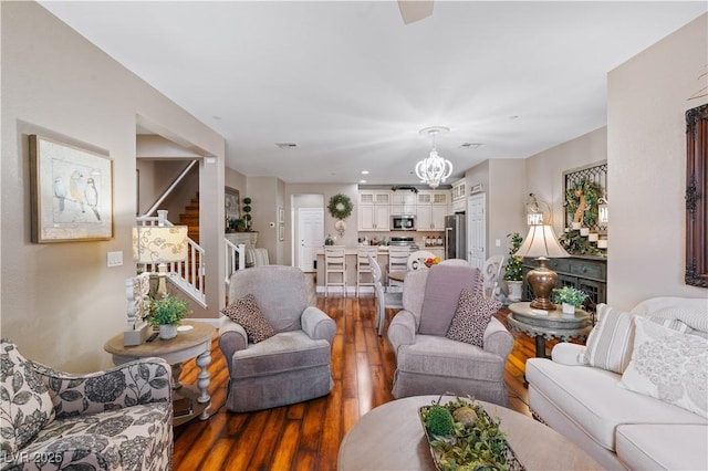 living room featuring stairway, a notable chandelier, wood finished floors, and visible vents