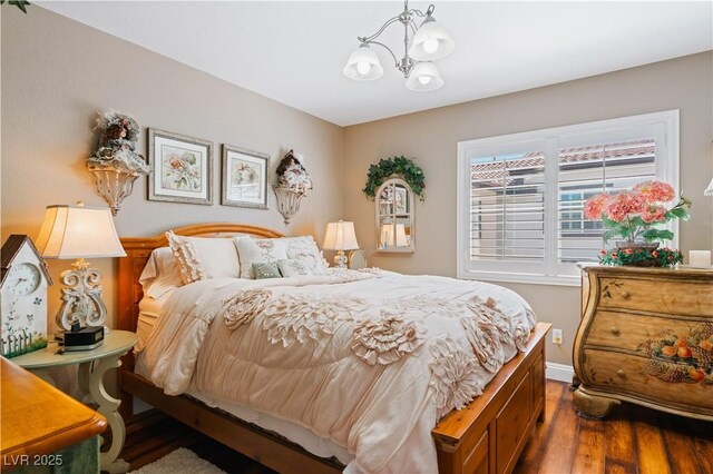 bedroom with a notable chandelier, baseboards, and wood finished floors