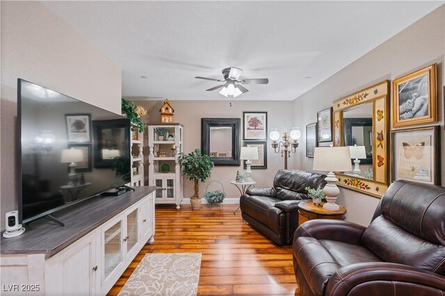 living area with ceiling fan, baseboards, and hardwood / wood-style floors