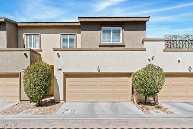 townhome / multi-family property with stucco siding, a garage, and driveway