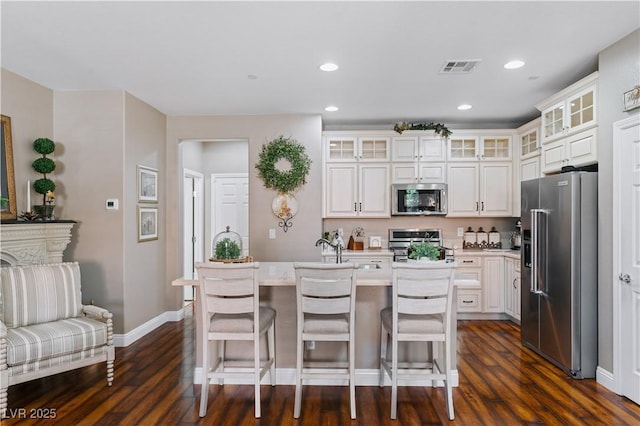 kitchen with visible vents, dark wood finished floors, light countertops, an island with sink, and appliances with stainless steel finishes