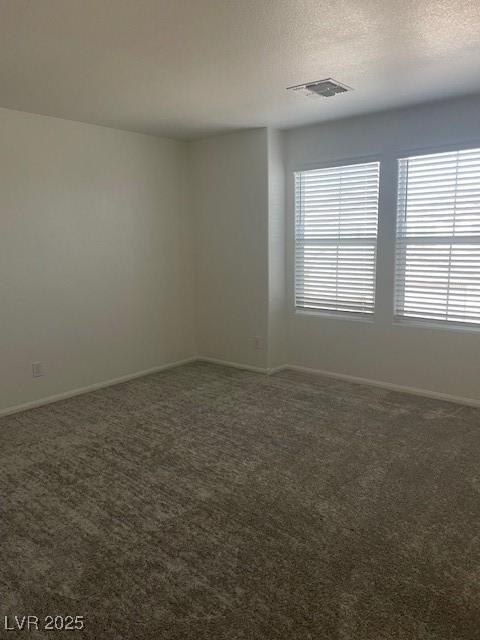 carpeted spare room with baseboards, visible vents, and a textured ceiling