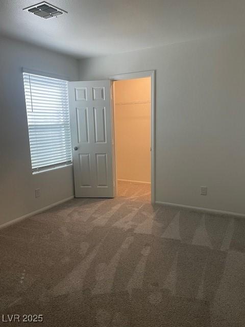 empty room featuring visible vents, carpet floors, and baseboards