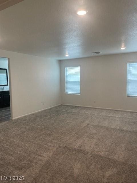 carpeted empty room with visible vents, baseboards, and a textured ceiling