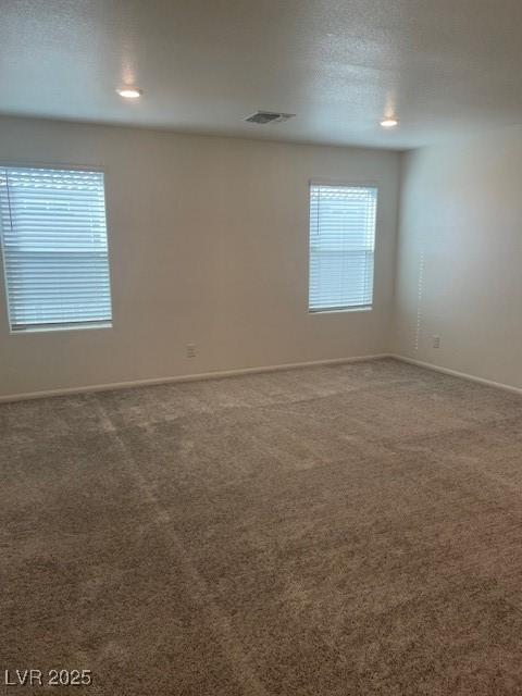 carpeted spare room featuring baseboards and visible vents