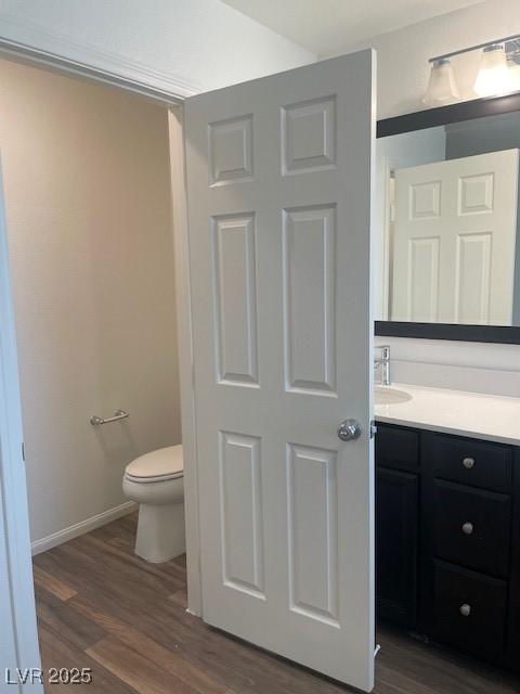 bathroom featuring toilet, vanity, baseboards, and wood finished floors