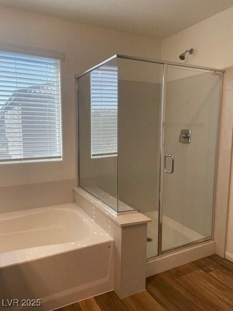 bathroom featuring a garden tub, wood finished floors, and a stall shower