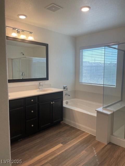 bathroom featuring visible vents, a shower stall, vanity, and wood finished floors