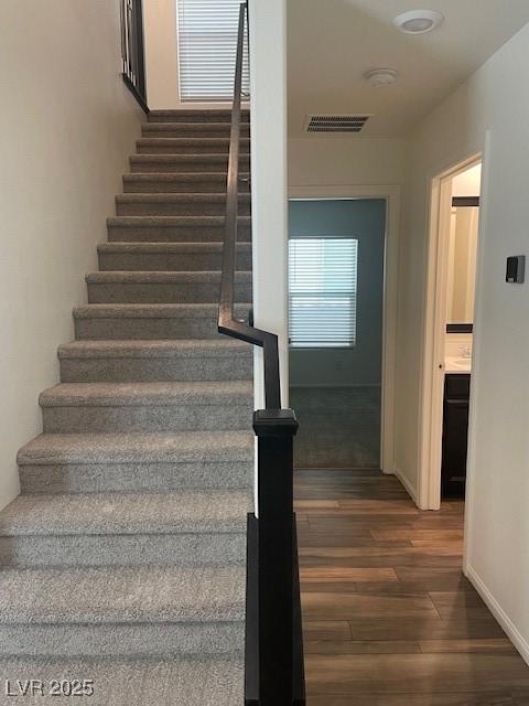 stairs featuring visible vents, baseboards, and wood finished floors