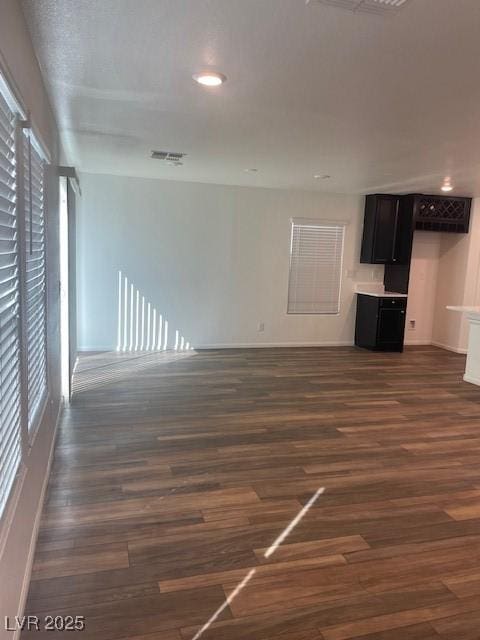 unfurnished living room with recessed lighting, visible vents, baseboards, and dark wood finished floors