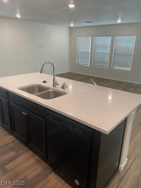 kitchen with a sink, dark cabinets, dishwasher, light wood-type flooring, and a kitchen island with sink