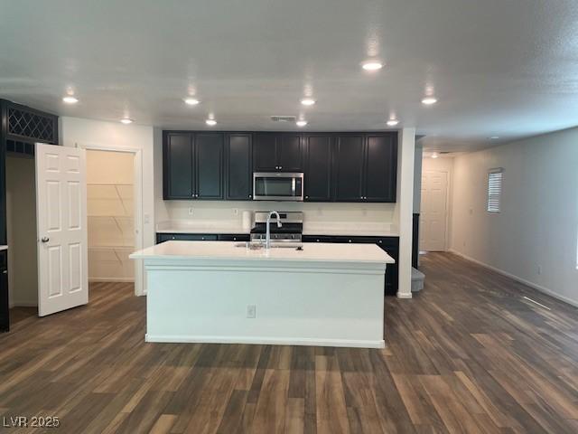 kitchen featuring stainless steel microwave, stove, dark wood-style flooring, and light countertops