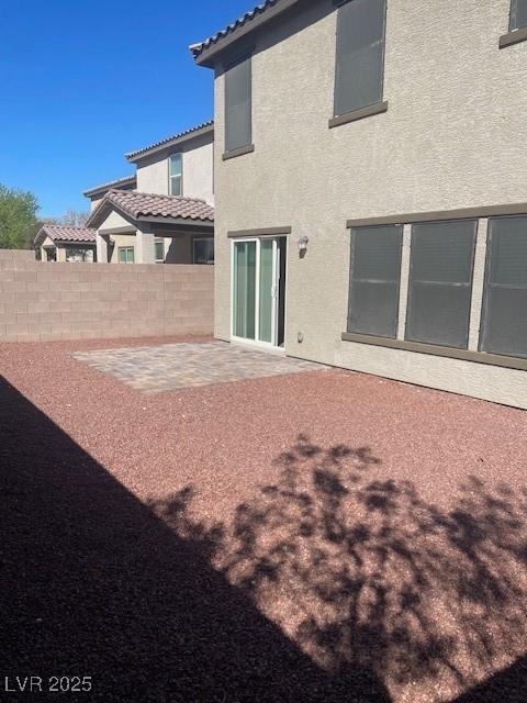 back of property with stucco siding, a tiled roof, a patio, and fence