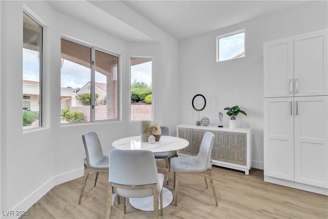 dining room featuring light wood-style floors, baseboards, and a wealth of natural light