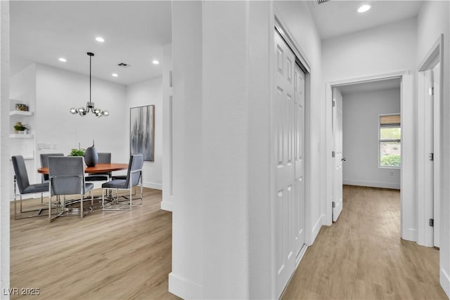 corridor with a notable chandelier, visible vents, recessed lighting, and light wood-style floors